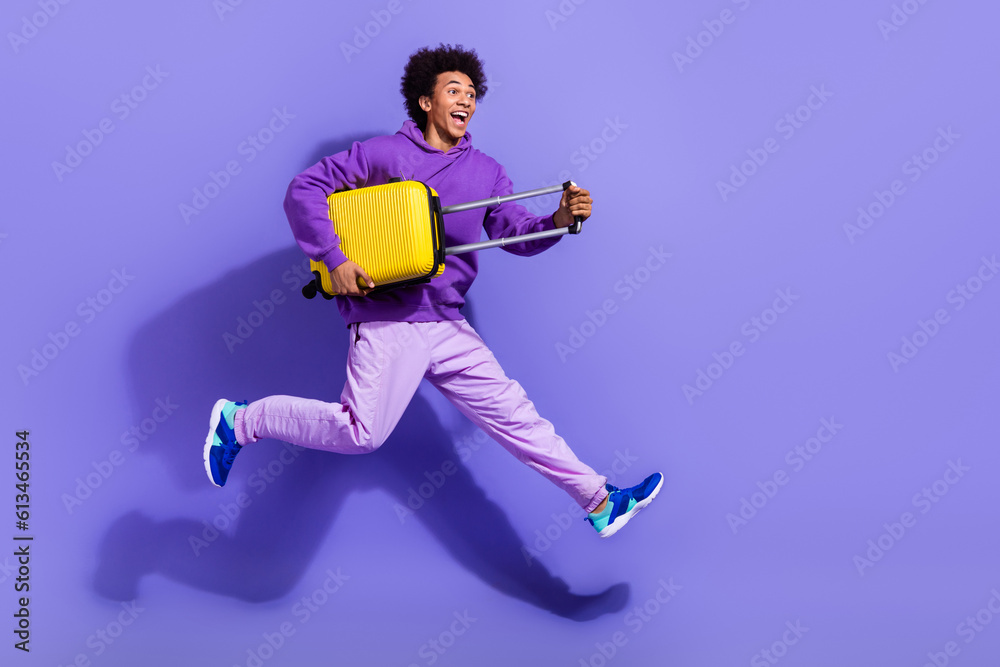 Poster Full size photo of funny excited person wear stylish pullover holding yellow baggage run empty space isolated on purple color background