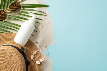 Enjoy sun responsibly. Overhead composition of unlabeled sunblock cream container, glasses, hat, shell bijouterie, palm leaf on light blue and sandy background, featuring empty area for text or advert