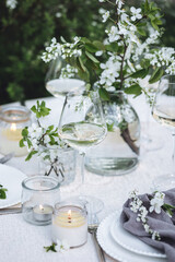 Rustic zero waste wedding decor with natural elements. Fresh spring blooming flowers, candles, linen napkins, wine glasses. Eco friendly decoration for the special holiday dinner. Romantic cozy place