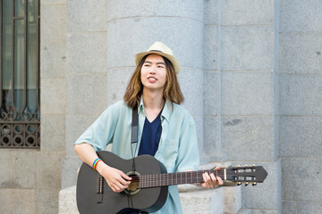Young street musician playing guitar and singing on a vibrant street