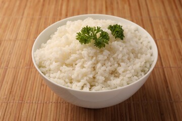 Bowl with delicious rice and parsley on bamboo mat