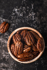 Pecan nuts on a rustic wooden table and pecan nuts in bowl.