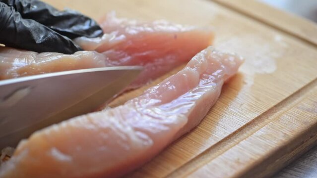 Chef hands cut chicken fillet with a knife on a wooden cutting board. Chef cooking healthy diet dinner with chicken meat.