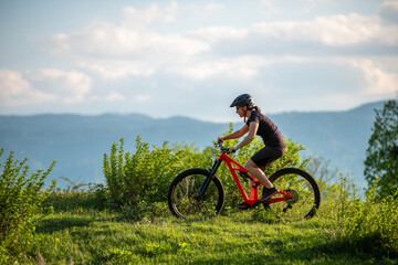 Fototapeta premium Female cycling on her mountain bike through the countryside on a sunny day.