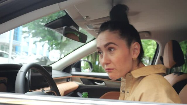Brunette woman driver secretly tries to drink strong beer from bottle in vehicle. Businesswoman neglects health and breaks traffic rules of safe drive