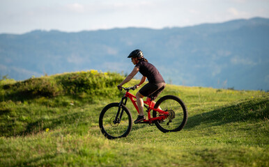 Obraz premium Female cycling on her mountain bike through the countryside on a sunny day.