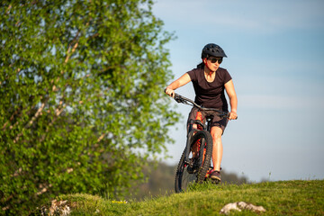 Fototapeta na wymiar Female cycling on her mountain bike through the countryside on a sunny day.