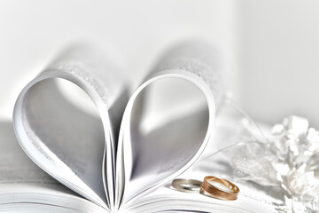 Wedding background.Blurred background of wedding rings and open book An open book with a heart folded from folded sheets - Powered by Adobe