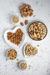 Different types of nuts on a plate in the shape of a heart. Assorted nuts on a white background. Top view.