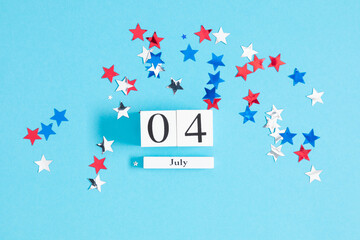 4th of July, USA Presidents Day, Independence Day. Flat lay top view of  celebration decor: wooden calendar, twinkling confetti on blue background with space, promotion or greeting message