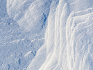 Beautiful winter background with snowy ground. Natural snow texture. Wind sculpted patterns on snow surface.