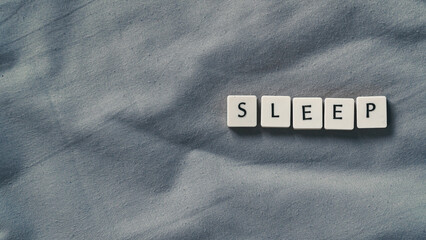 Sleep concept. Sleep lettering on a soft bed sheet. Copy space for text template for presentation