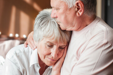 Worried senior woman embracing upset old man