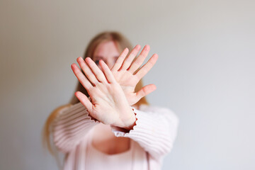 Woman showing stop symbol. Close up photo of female hands shows No gesture by hand. The girl covers...