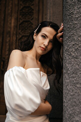 Fototapeta premium A girl in a white dress with a deep look near an old building