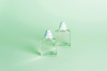 Two bottles of perfume on light green background. Close up