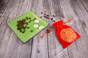 Coffee beans on a green saucer with a red pouch next to it, wooden background, photo at an angle