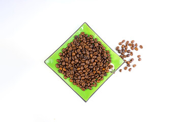 Coffee beans on a green square saucer, white background
