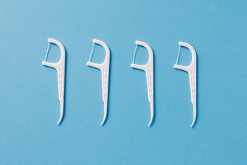 Set of white dental toothpicks with dental floss on blue