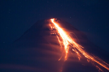 volcano erupting at night spewing lava