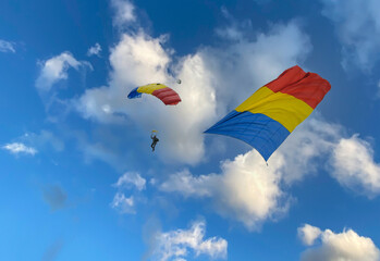 Parachute in flight and the flag of Romania. National Day of Romania - concept.