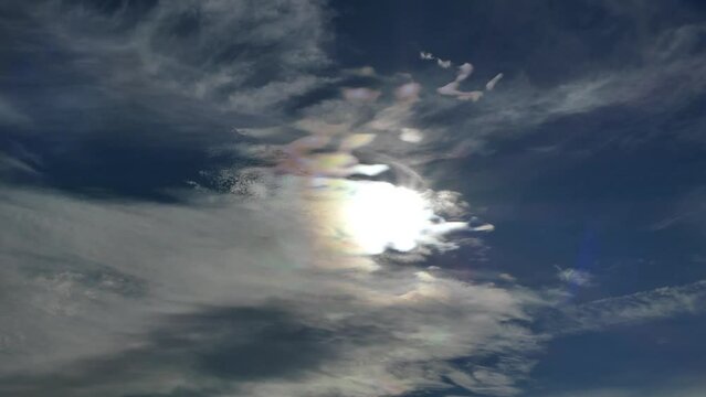 Natural blue sky with colorful decorative clouds moving very slowly - Cloud iridescence, irisation around sun. Sunny autumn calm sky with colorful pearl colors - optical phenomenon at accelerated pace