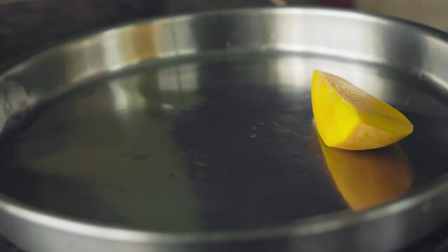 A closeup of cut or sliced juicy mango pieces being served on a steel plate
