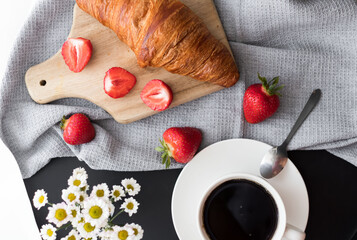Breakfast with coffee, croissants and strawberries on the table. Morning