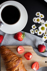 Breakfast with coffee, croissants and strawberries on the table. Morning