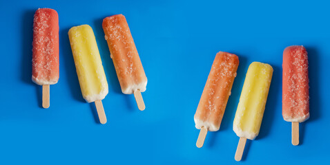 six colorful fruit ice-cream popsicles over blue background with copy space 