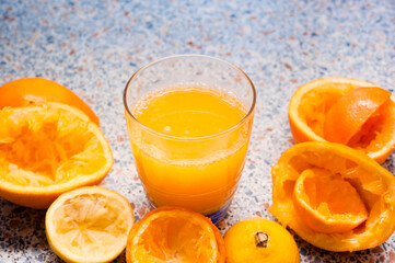 glass of orange citrus juice with empty peels of citruses standing on table, citrus orange juice after prepaparation