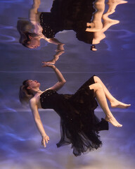 girl touches the surface of the water underwater