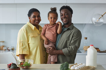 Portrait of African American family of three smiling at camera standing in the kitchen