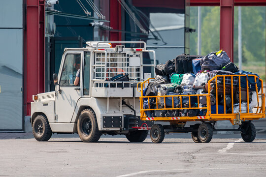 Close-up tow truck pulling baggage cart at airport apron