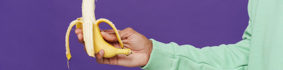 Black man's hand holding and showing banana at camera