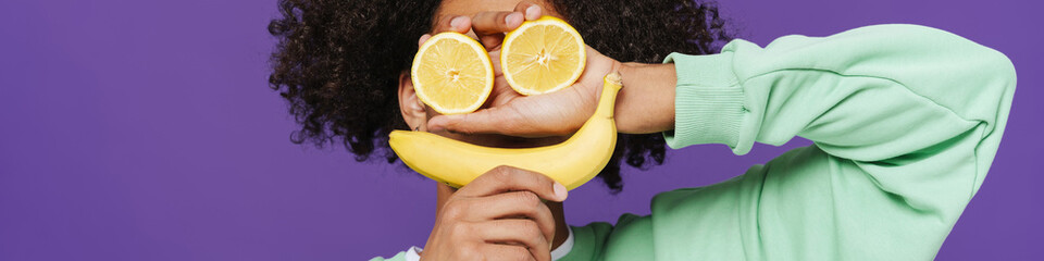 Young caribbean man making fun with fruits on camera