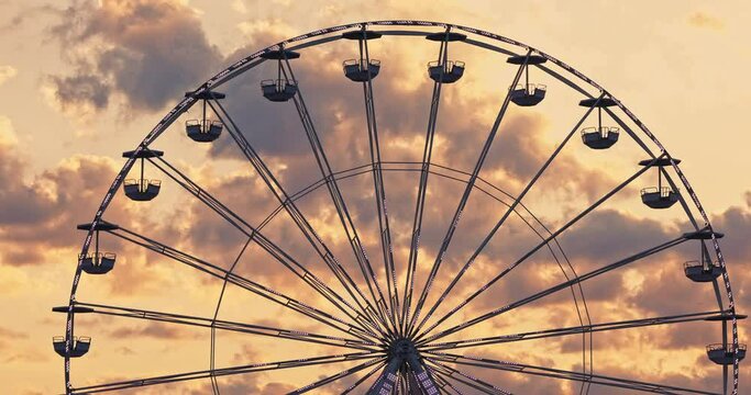 Spinning Ferris Wheel in amusement park and scenic sunset clouds in sky 4K cinematic video