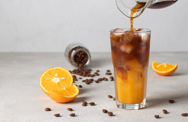 Bumble coffee with ice on light gray background. Cold coffee is poured into a glass with orange...