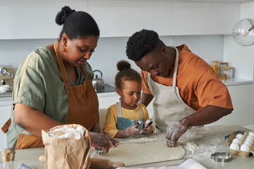 African American family using baking mould to make cookies together in the kitchen