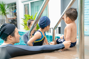 Child boy and girl swimming with mom in condominium swimming pool