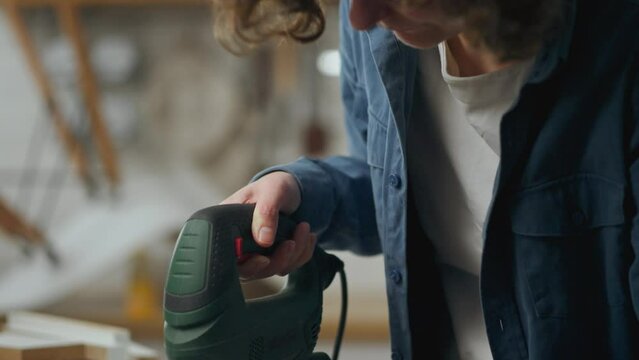 Assembling, Active caucasian woman Carefully cuts wood with a power tool with a jigsaw In a residential apartment, Active young worker Collects fittings In a residential area, self-assembly
