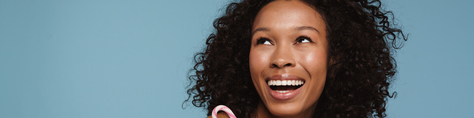 Shirtless black woman laughing while posing with candy