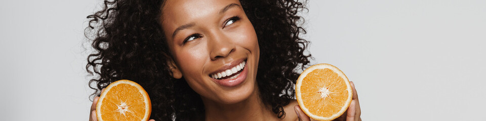 Shirtless black woman laughing while making fun with orange