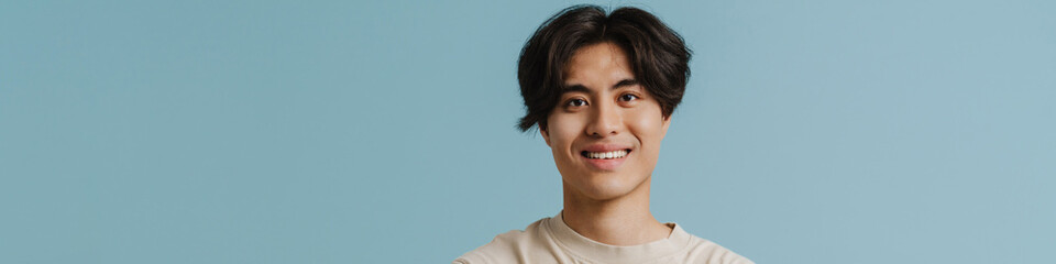 Young handsome smiling asian boy with folded arms