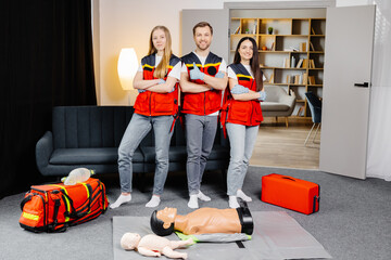 Group of people with cpr dummy looking at camera and smiling after first aid training class