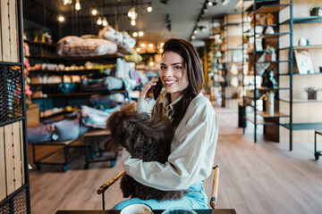 Beautiful and happy young woman sitting in modern pet shop cafe bar and enjoying in fresh coffee...
