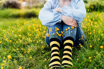 Close up young female wearing jeans and striped black and yellow socks with flowers inside sitting...