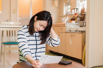 電気料金の高騰で頭を抱える若い女性