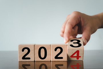 New Year 2024,Start up,Set up new plan,business,goal,target concept.,Hand Flipping wooden block with number 3 to number 4 meaning to 2023 to 2024.