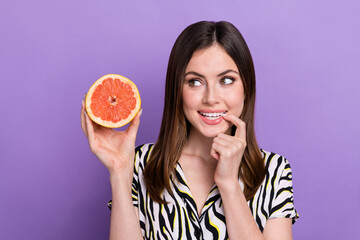 Photo of young girl admire wish straight long hair look interested wish eat healthy grapefruit drink juice isolated on purple background